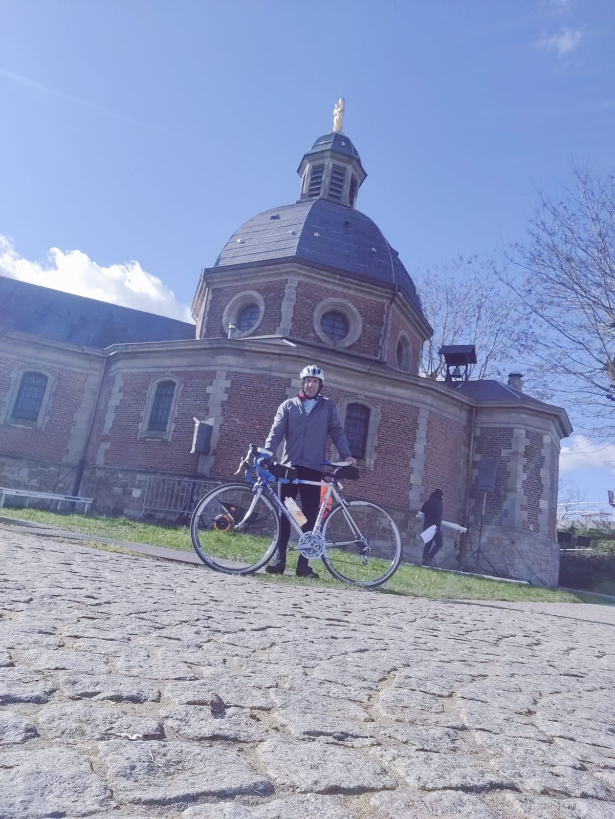 Cyclist and bike standing in front of the chapel at the Muur van Gerardsbergen